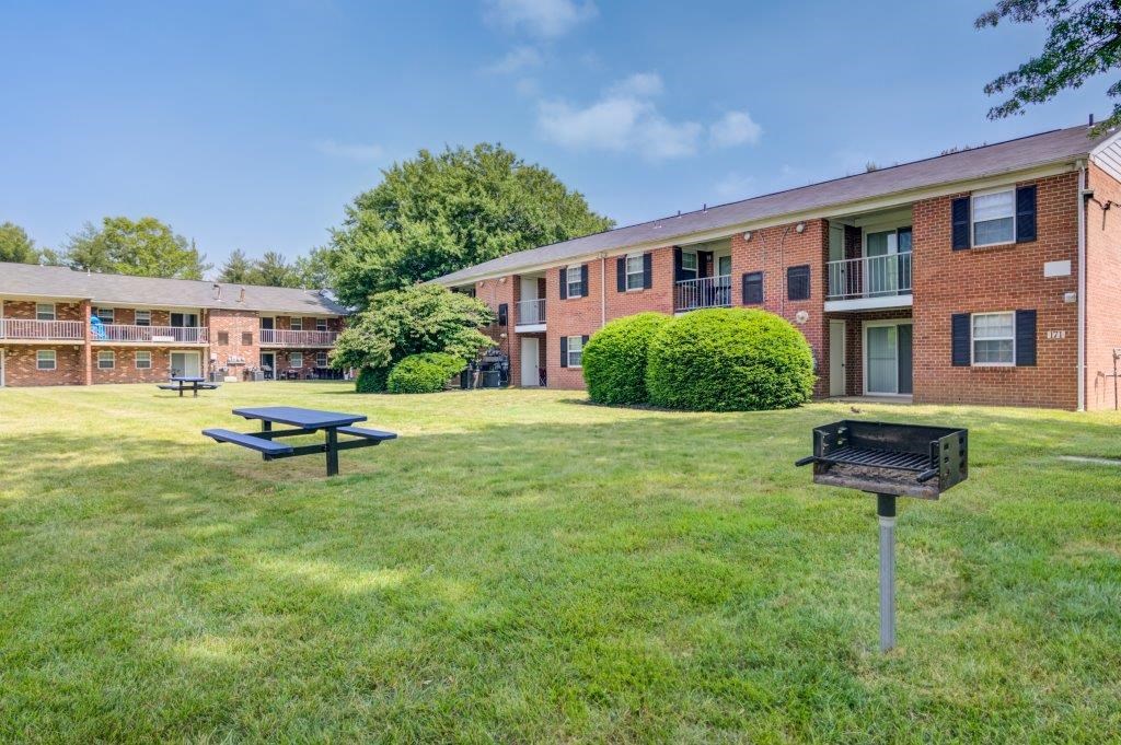 a picnic table and a grill in front of an apartment building