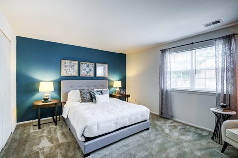 a bedroom with a bed and a blue wall and a window