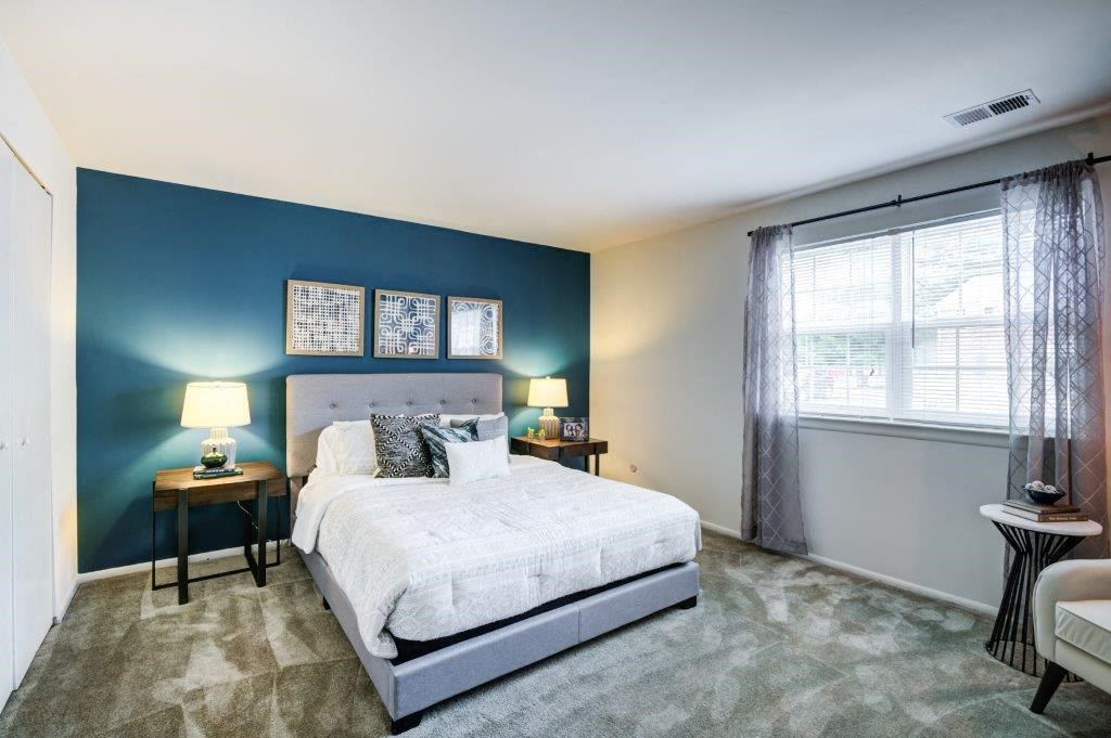 a bedroom with a bed and a blue wall and a window