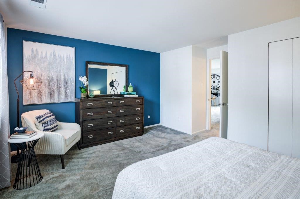 a bedroom with a blue wall and a white bed