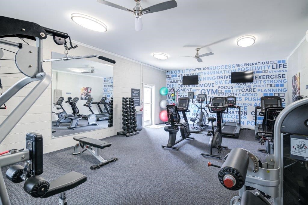 a gym with various exercise equipment and a mirror