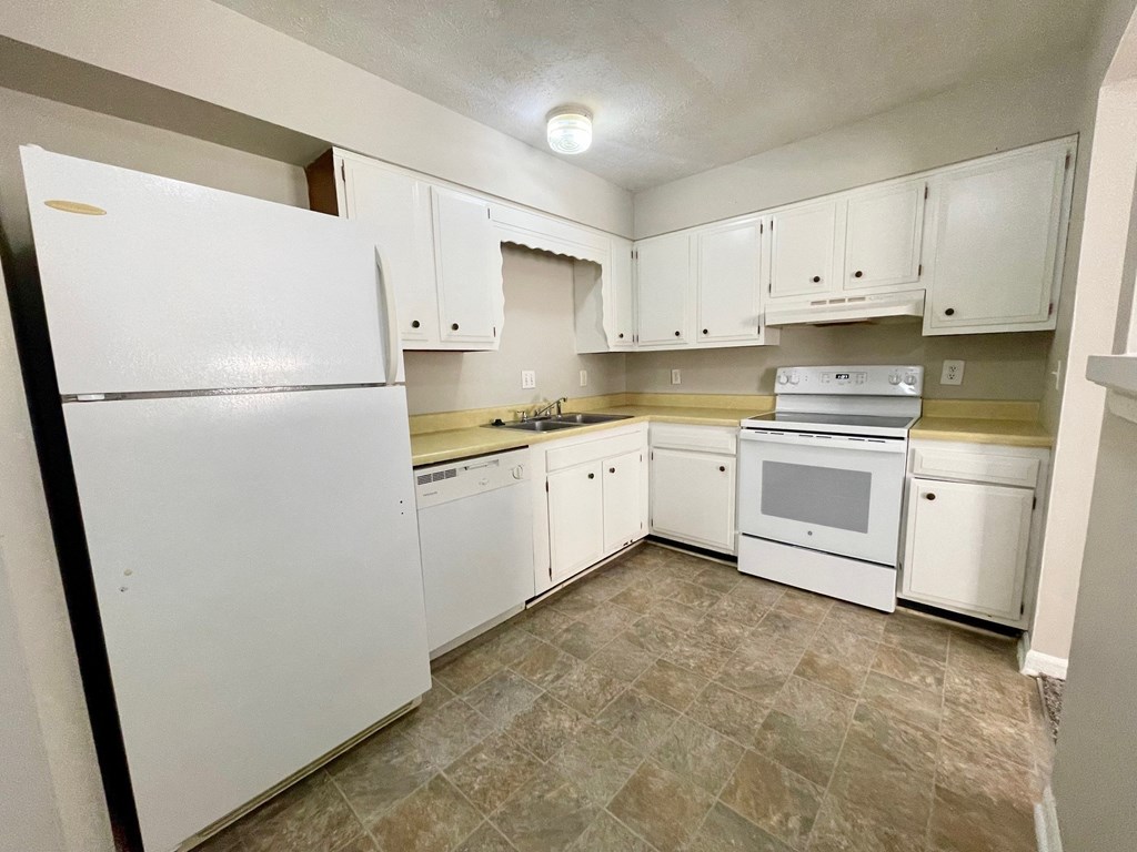 an empty kitchen with white appliances and white cabinets