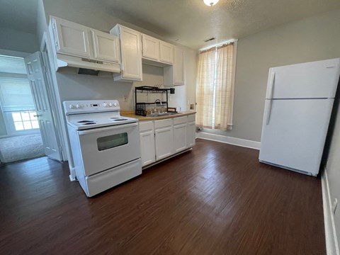 A kitchen with white appliances and wooden floors.