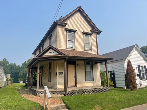 A two-story house with a porch and a mailbox on the front door.