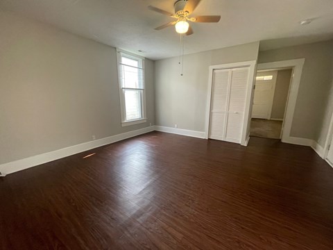 A room with a ceiling fan and wooden flooring.