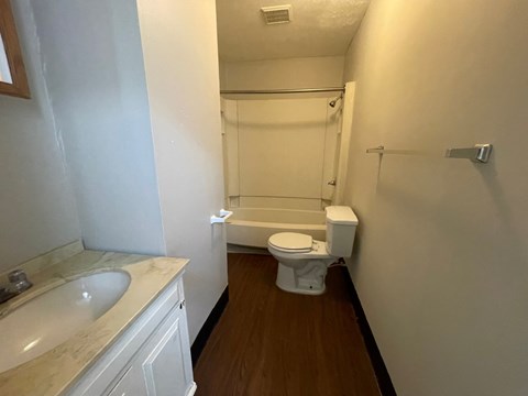 A white toilet is in a bathroom with a white sink.