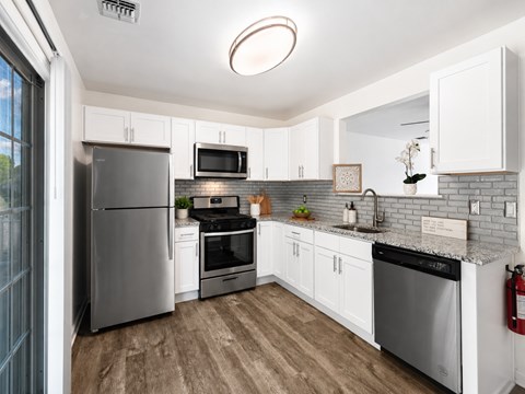 A modern kitchen with white cabinets and stainless steel appliances.