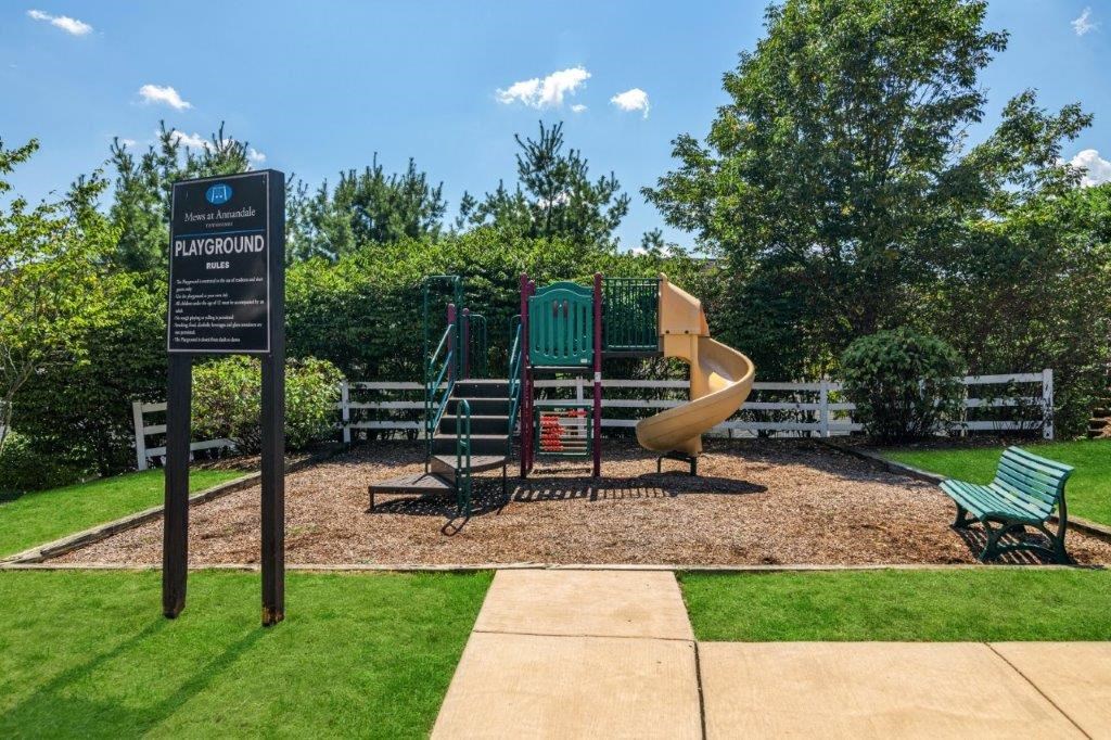 a playground with a slide and chairs in a park