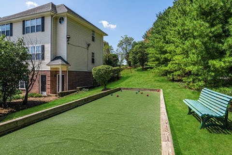a backyard with a lawn and a house with a bocce ball court