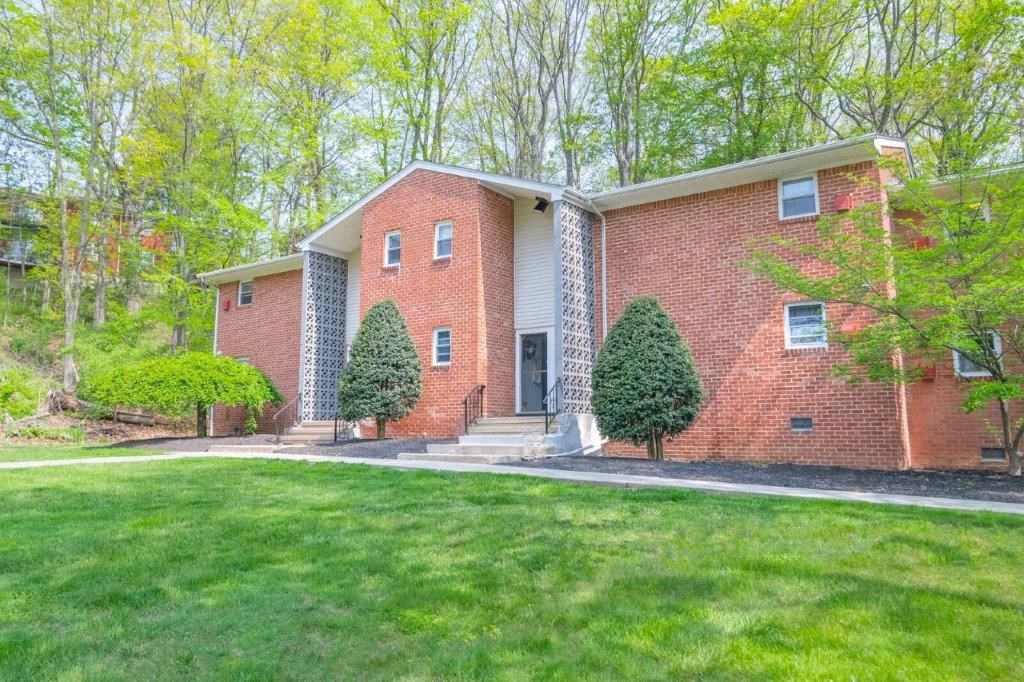 the front of a brick house with a lawn and trees