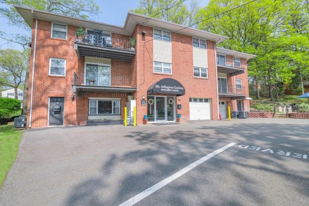 the front of a brick apartment building with a parking lot