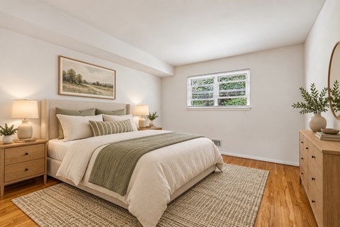 A bedroom with a large bed, two nightstands, and a painting on the wall.