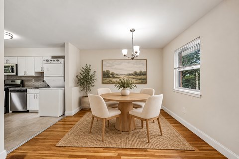 A dining room with a table set for two and a painting on the wall.
