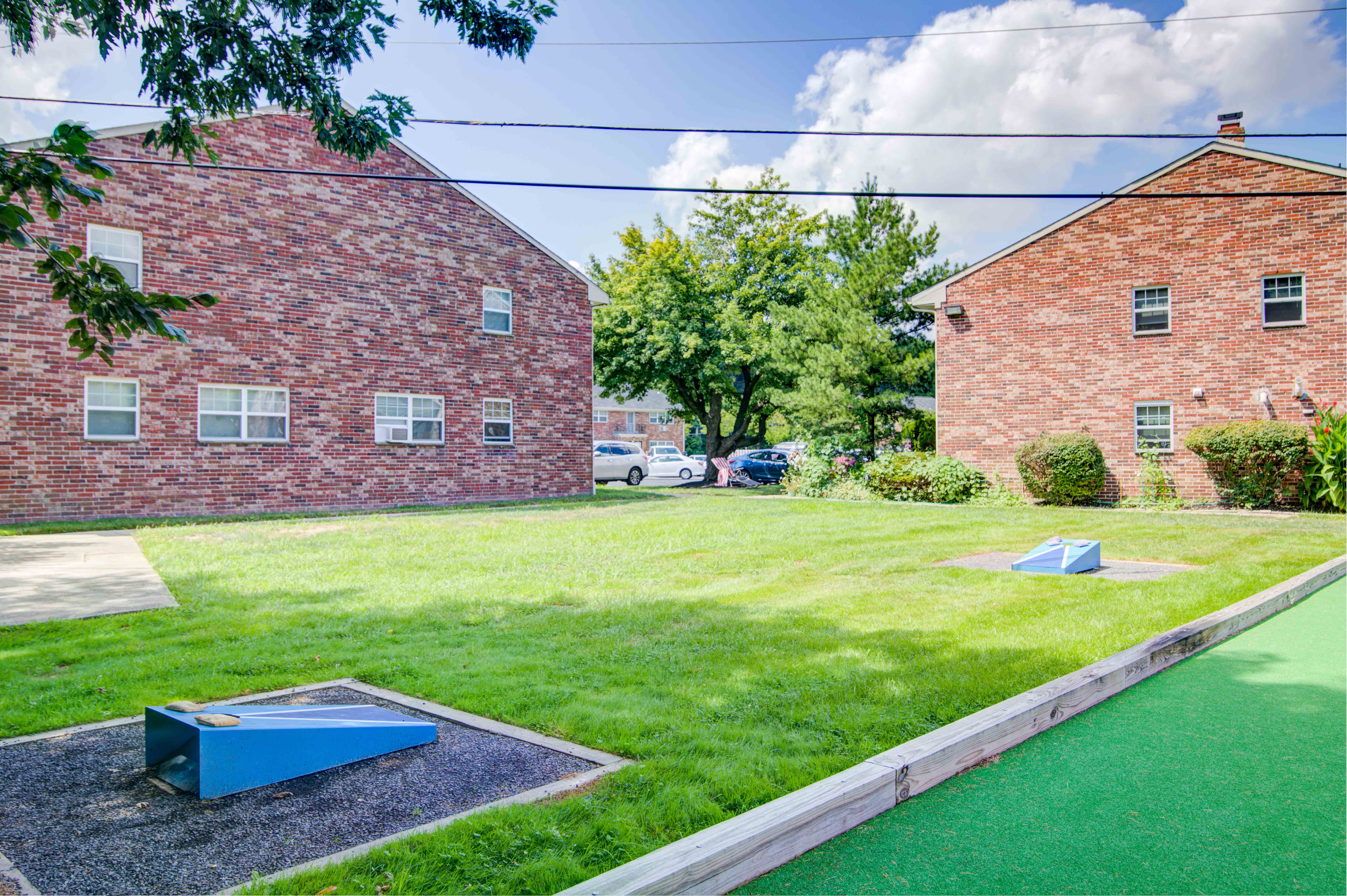 a yard with two trampolines in the grass next to two brick buildings