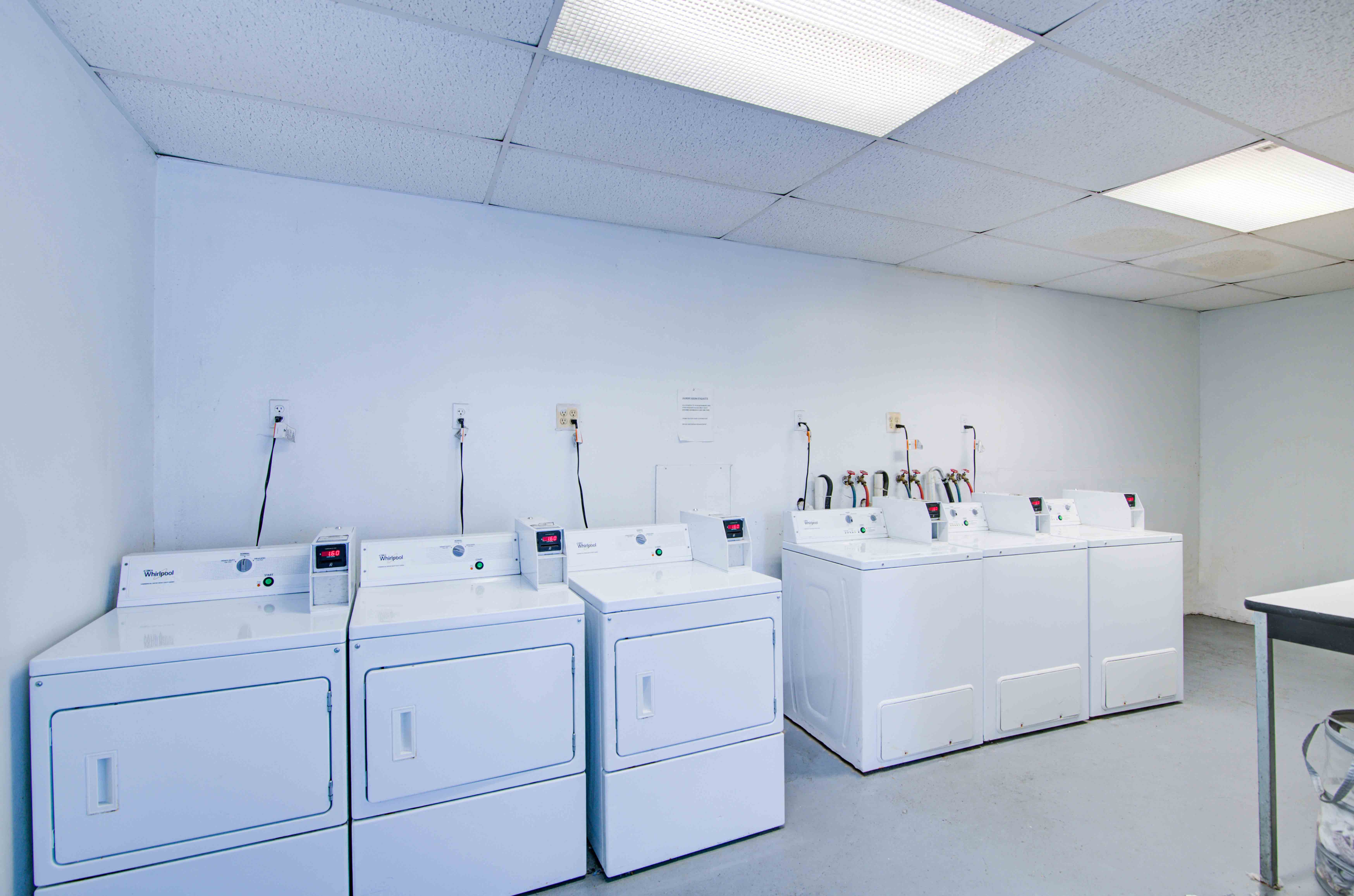 a row of washers and dryers in a room with four washing machines