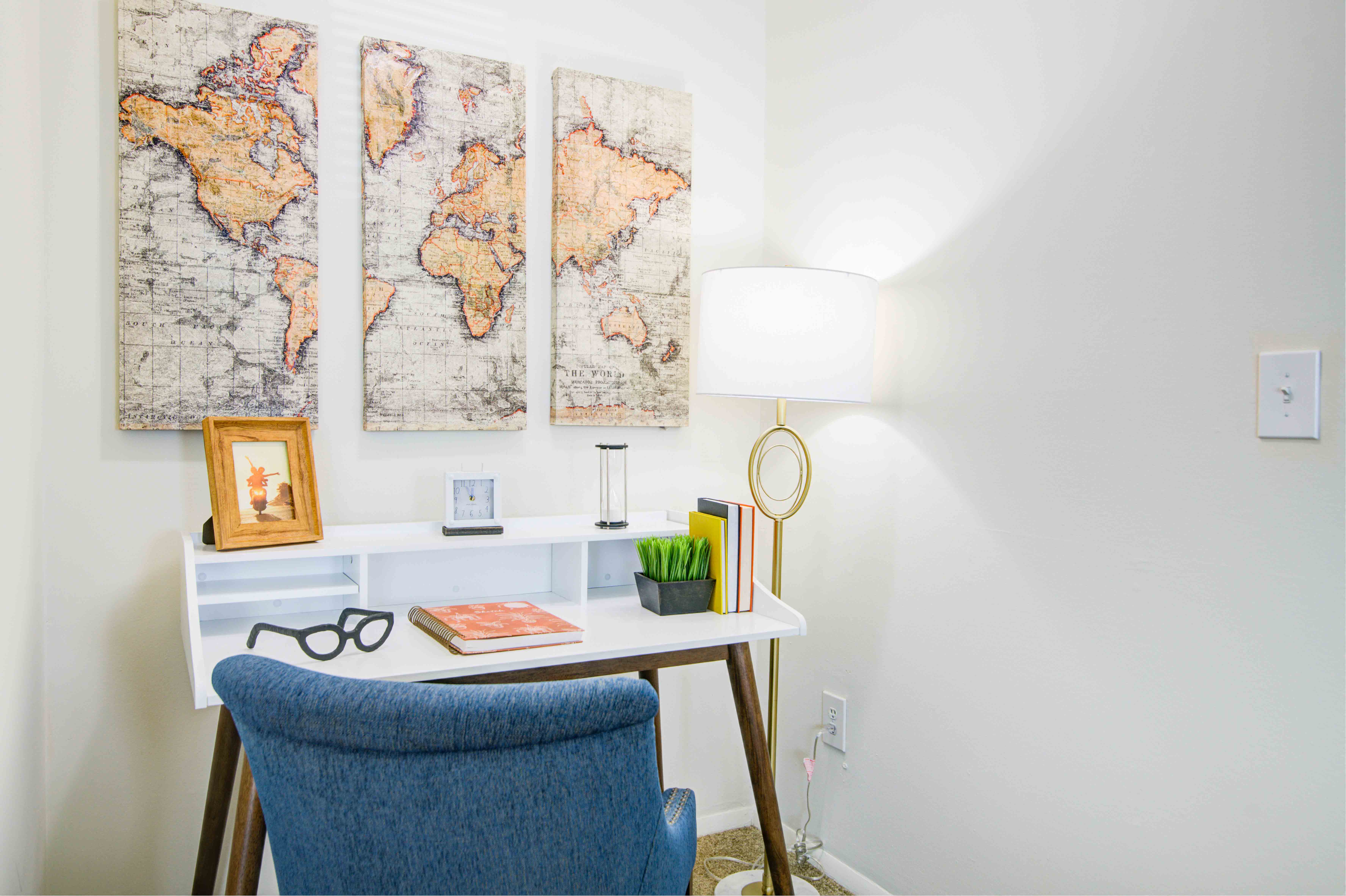 an office with a desk and a chair and three maps on the wall
