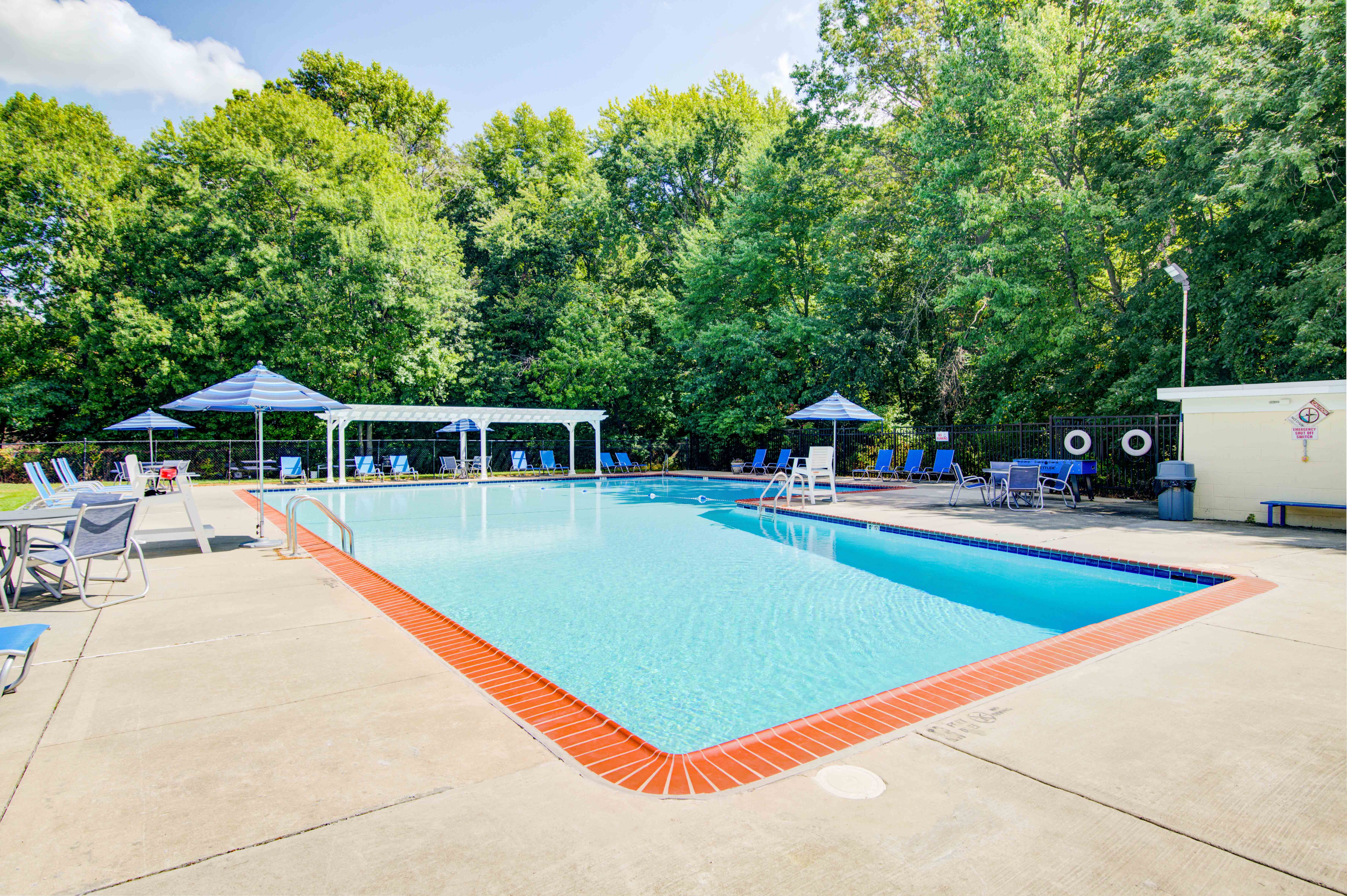 a resort style pool with chairs and umbrellas and trees