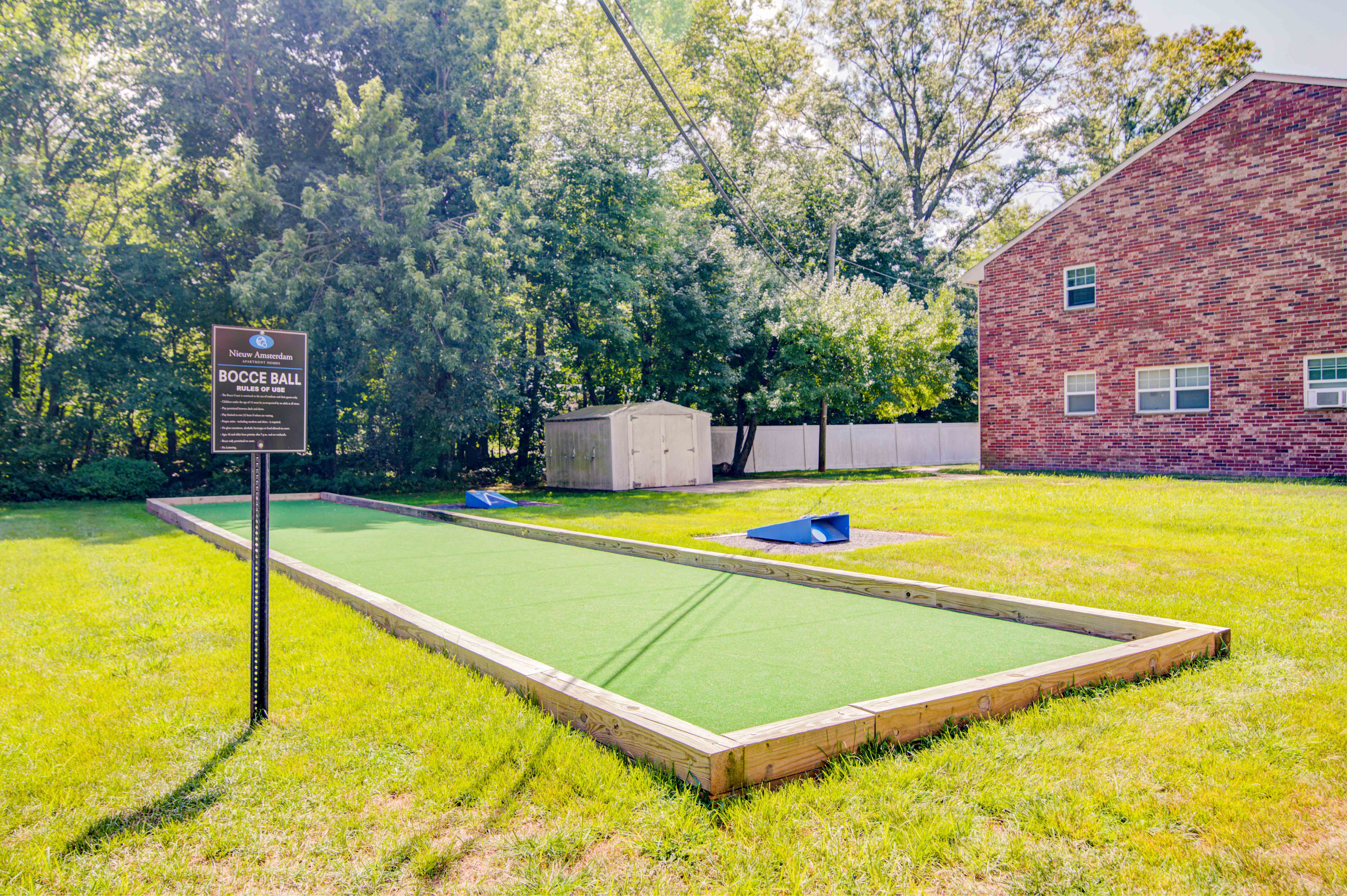 a backyard with a tennis court and a sign in the grass