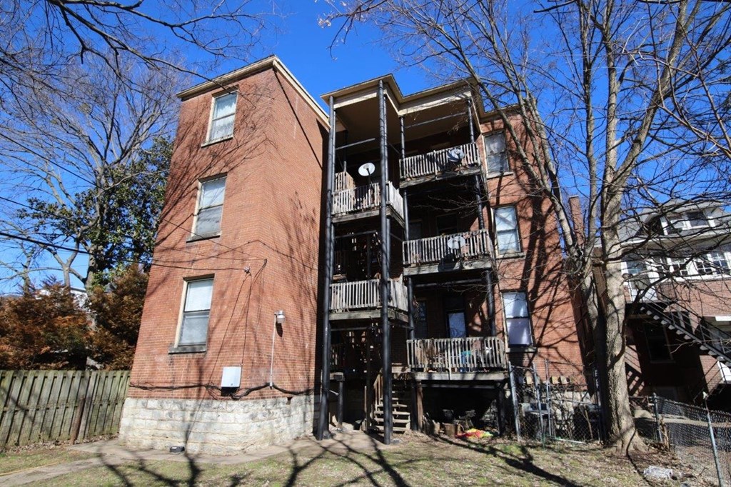 an old brick apartment building with stairs and trees