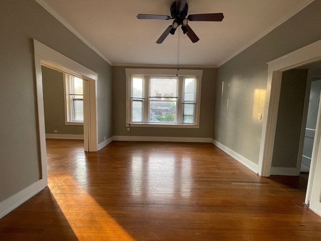 an empty living room with wood floors and a ceiling fan
