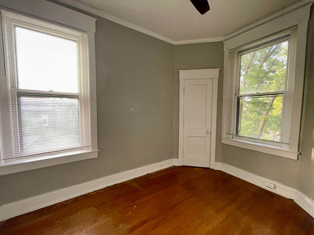 an empty room with a door and two windows