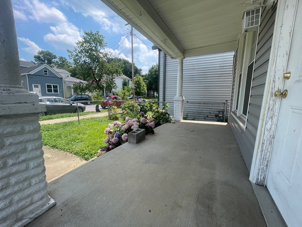 the front porch of a white house with flowers on it