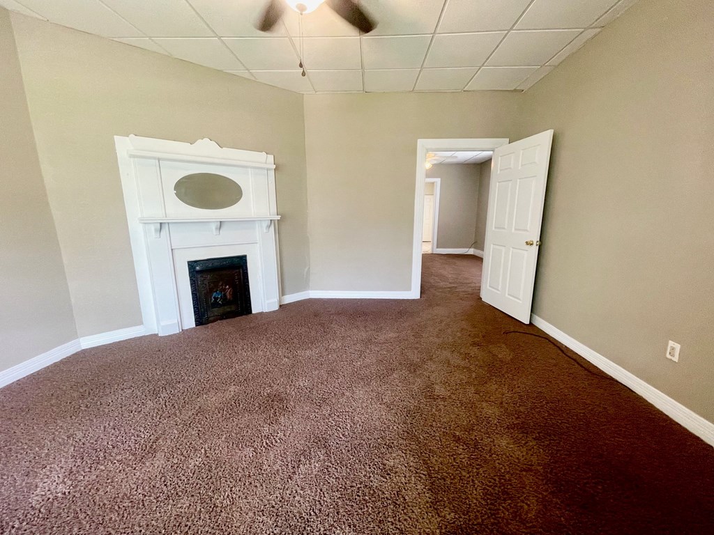 an empty living room with a fireplace and carpeted flooring
