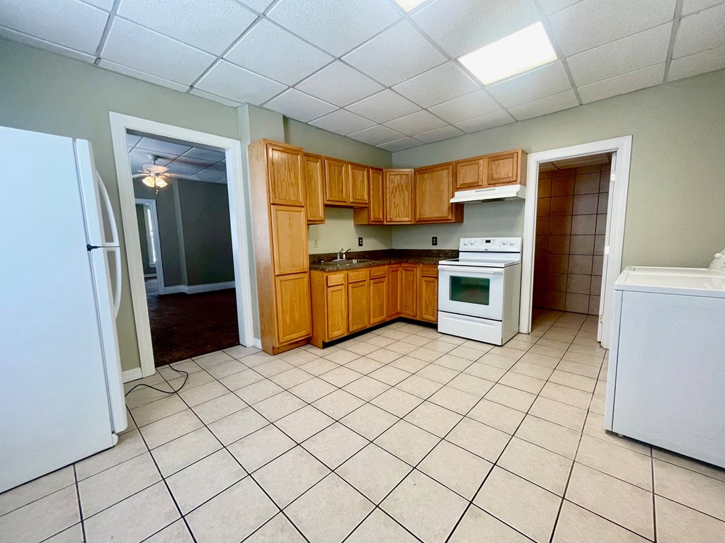 an empty kitchen with wooden cabinets and white appliances