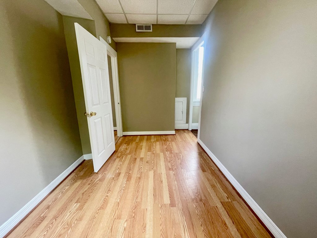 an empty hallway with wood floors and green walls