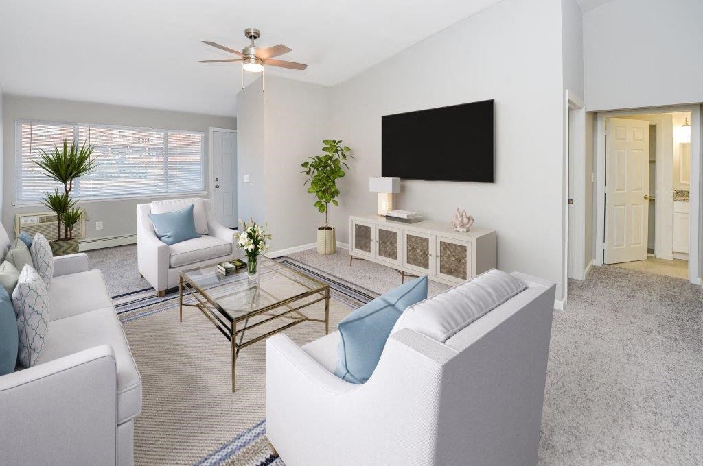a living room with white furniture and a television