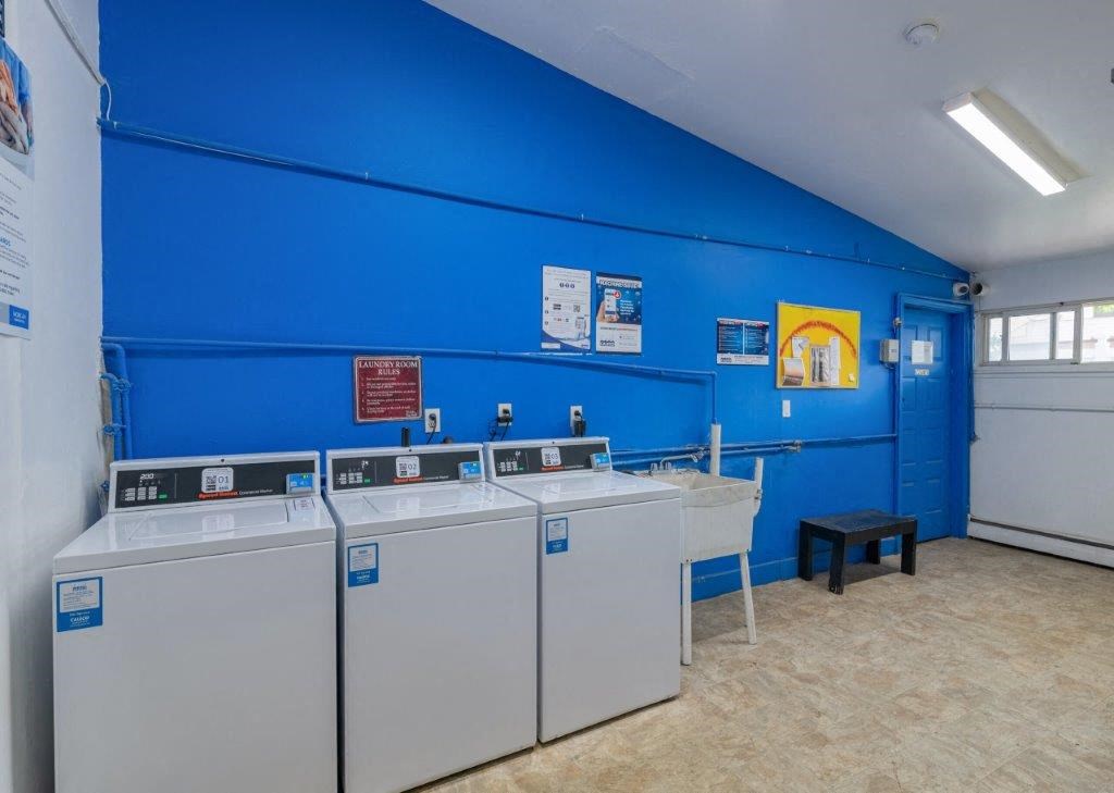four washers and dryers in a laundry room with a blue wall