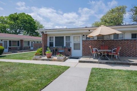 a patio in front of a brick house with an umbrella
