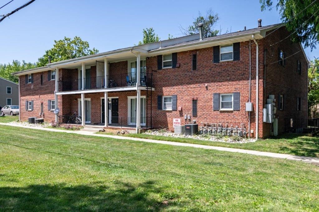 a red brick apartment building with a green lawn