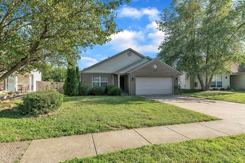 the front of a house with a lawn and trees