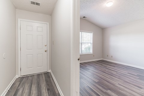 an empty bedroom with a white door and wood flooring