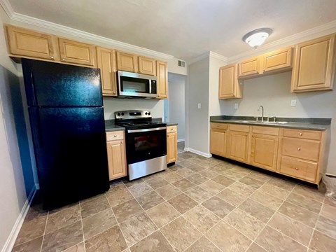 a kitchen with wooden cabinets and a black refrigerator
