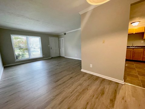 an empty living room with wood floors and a window