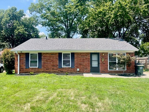 a small brick house with a yard and trees