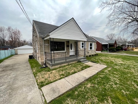A small house with a porch and a fence in front.