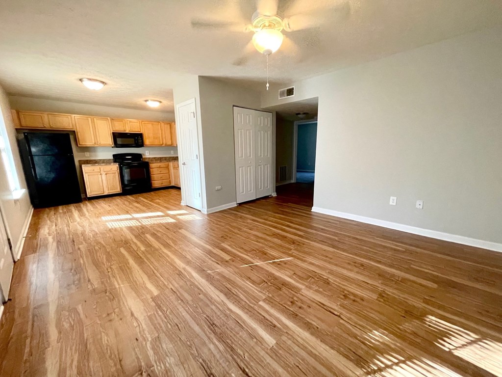 a living room and kitchen with wood flooring and a ceiling fan