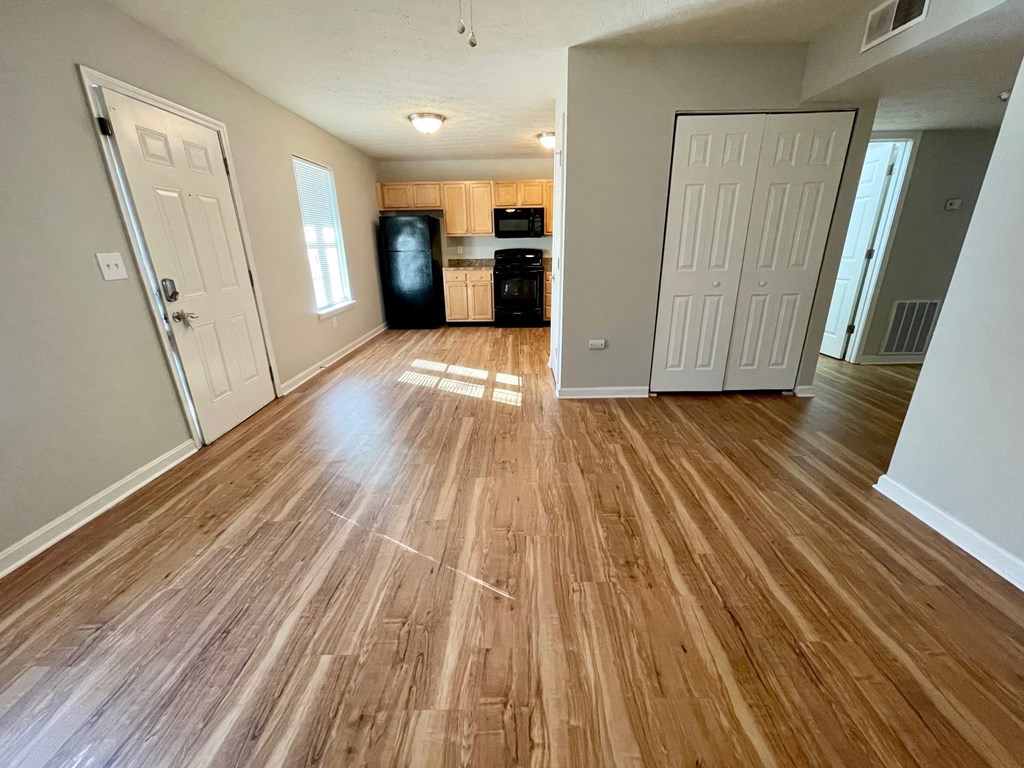an empty living room and kitchen with wood flooring