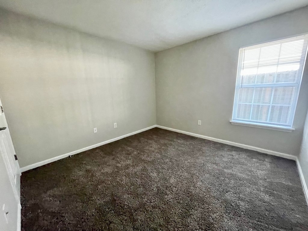 an empty bedroom with carpet and a window