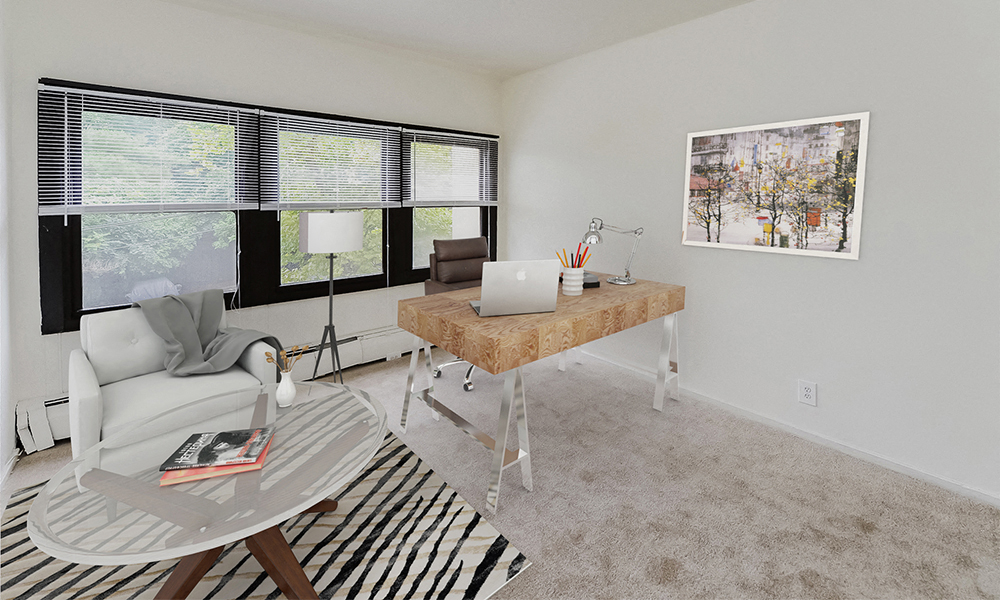 a living room with a couch and a desk with a laptop