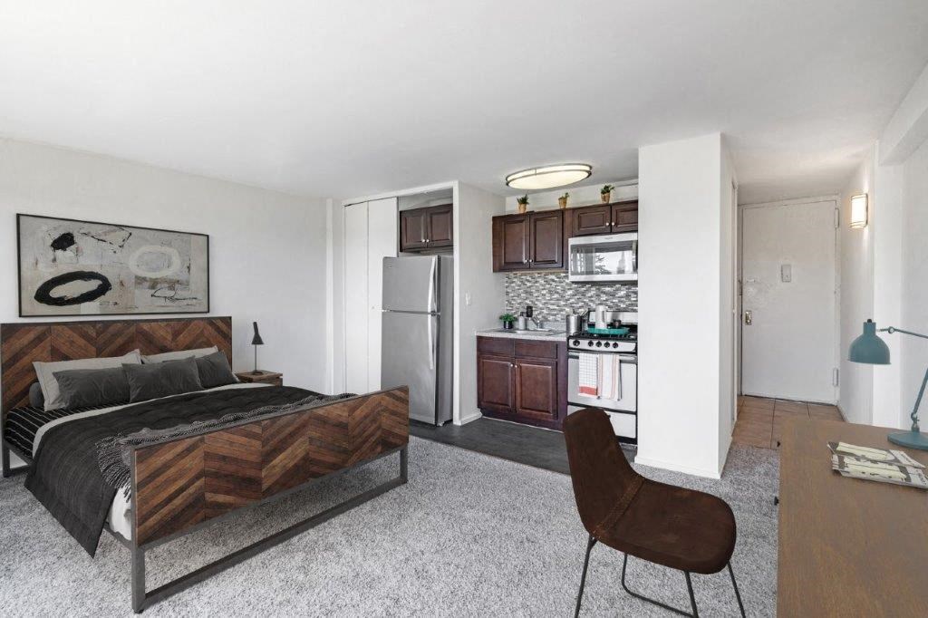 a bedroom with a bed and a kitchen with a refrigerator