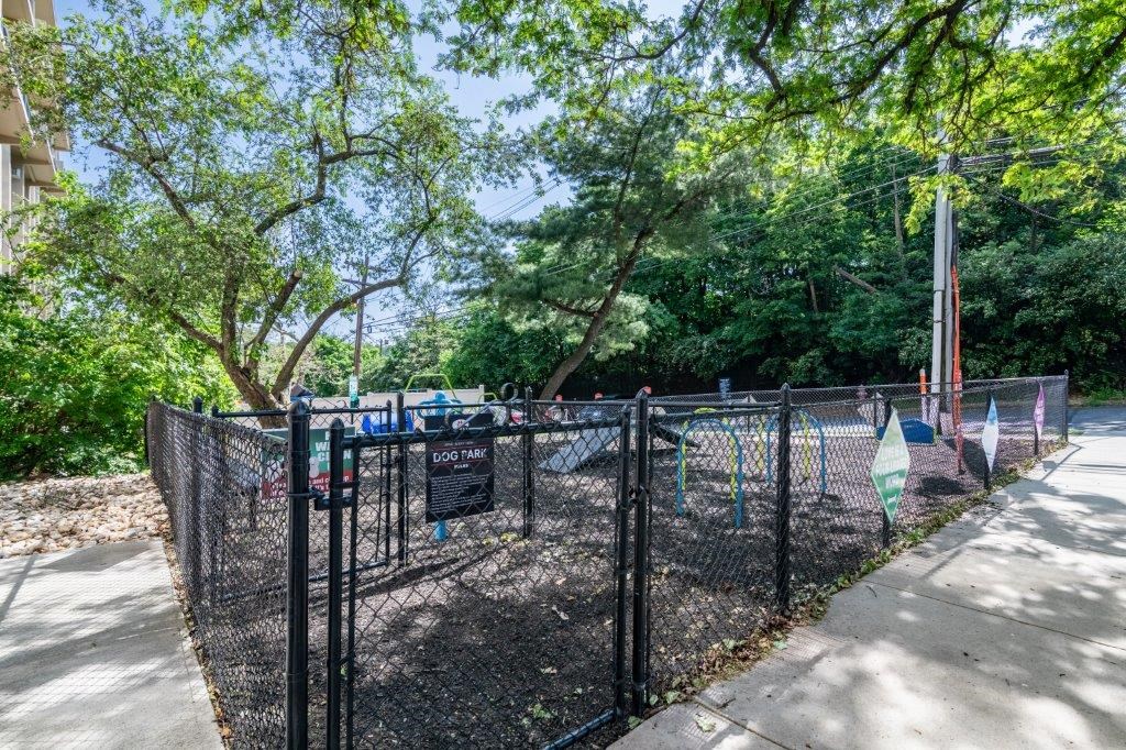 a fenced in park with a playground and trees