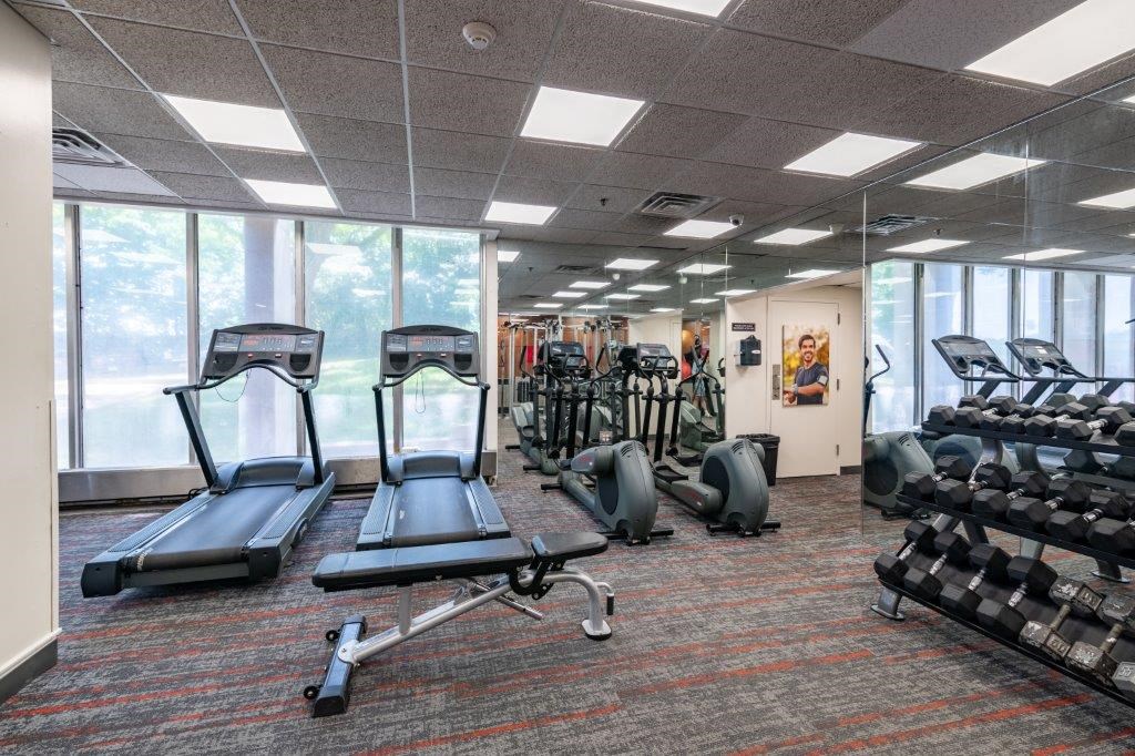 a gym with cardio equipment and windows in a building