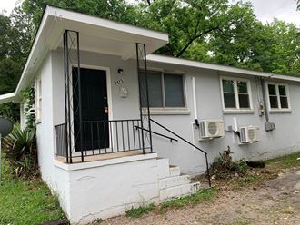a white house with a black door and a porch