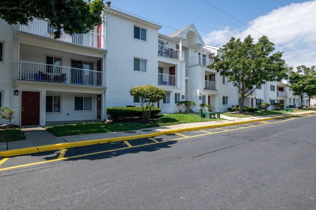 an empty street in front of some white apartment buildings