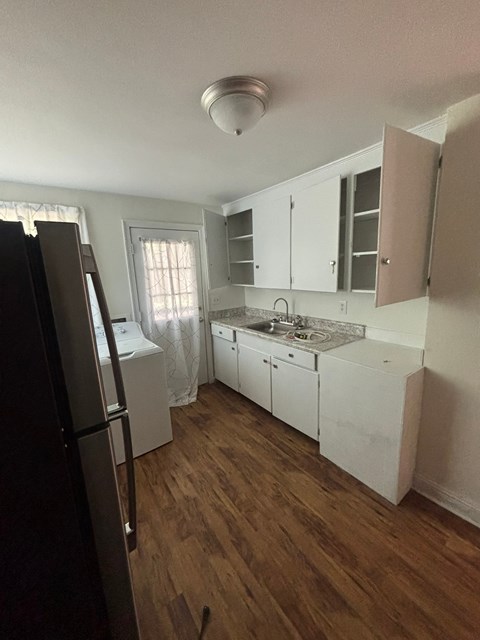 A kitchen with white cabinets and a black refrigerator.