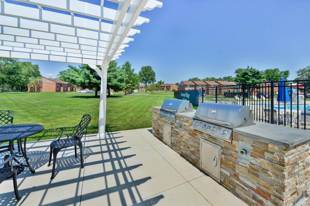 the outdoor patio has a grill and a table with chairs